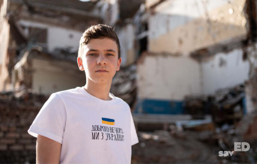 Ukrainian teenager in front of a destroyed school after Russian aggression